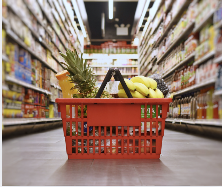 a shopping basket filled with fruit and vegetables sits in the middle of a supermarket aisle